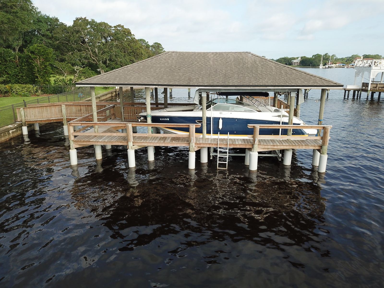 Boathouse with protected pilings and a boat on the lift