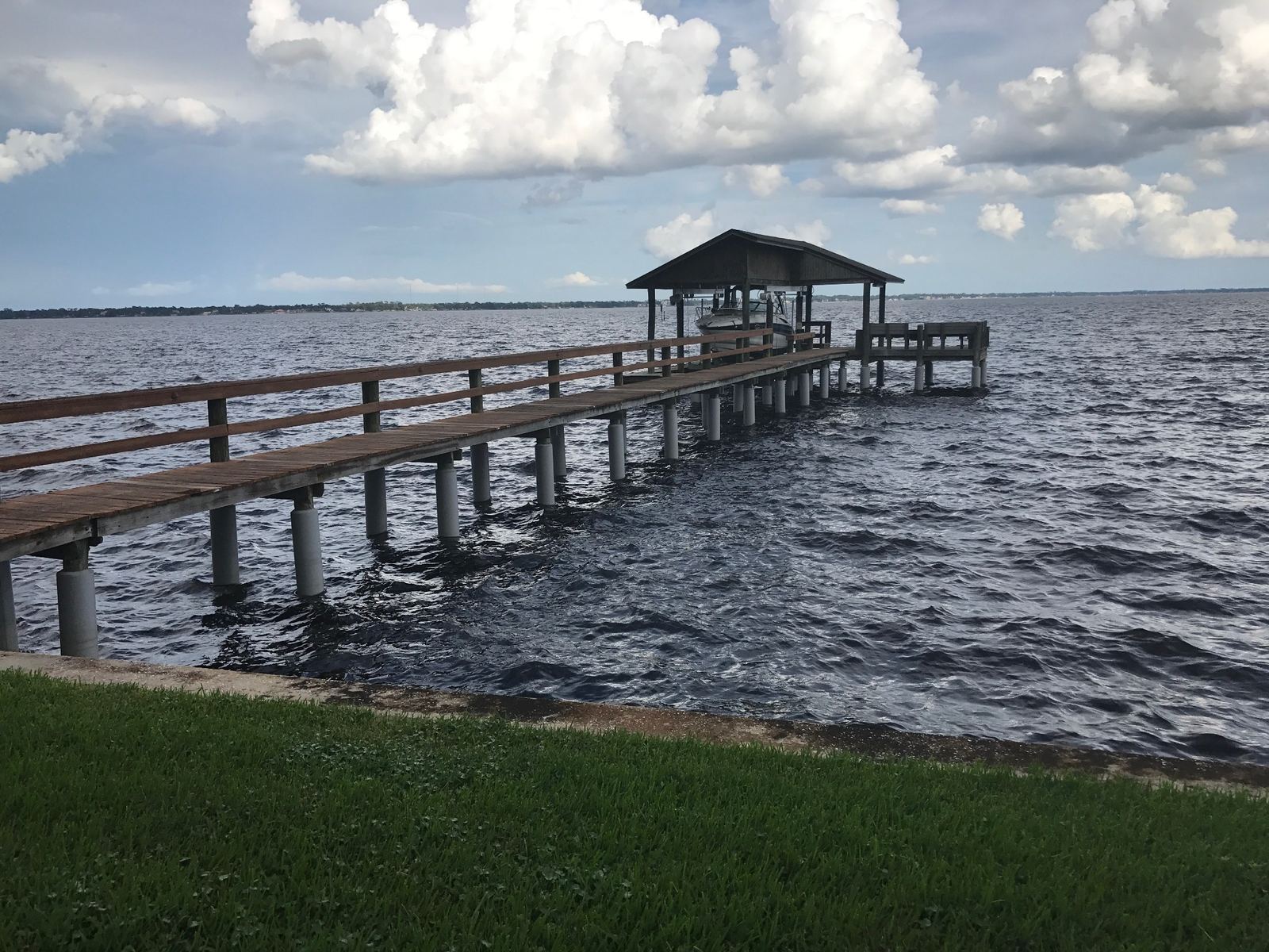 Long pier on protected pilings leading to a boathouse
