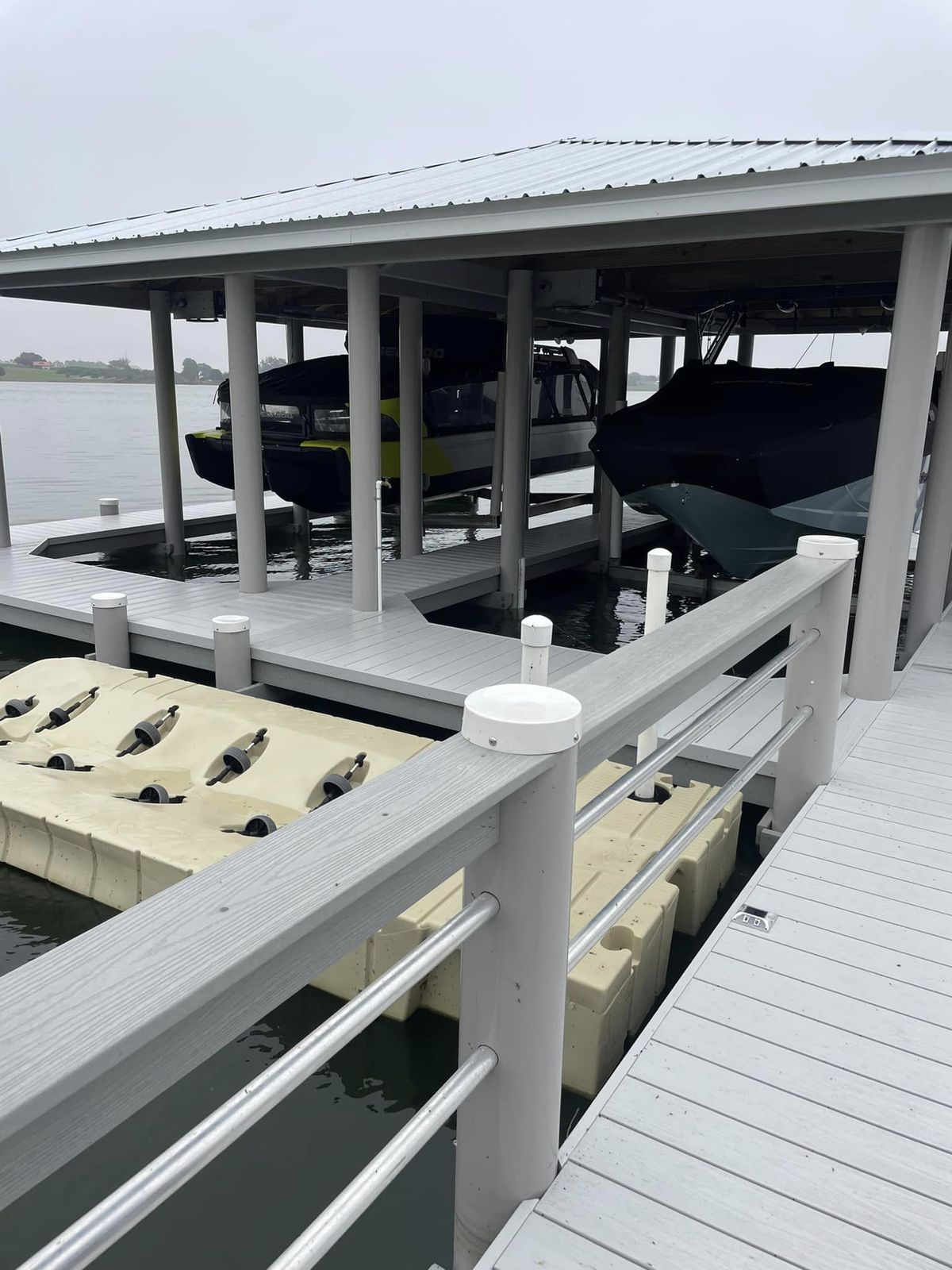 Boathouse with two boats on lifts and aluminum railing