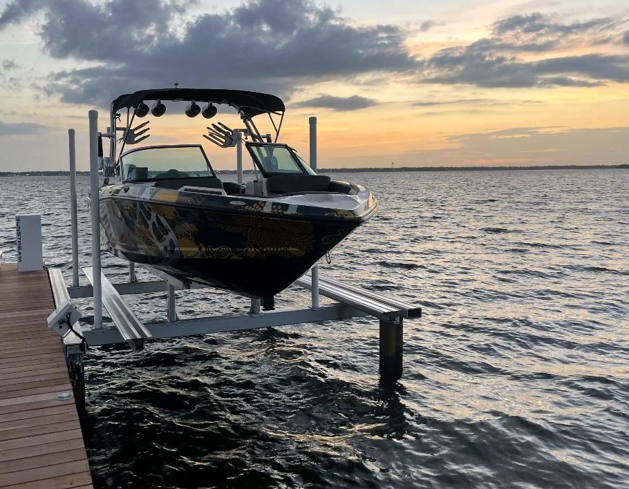 Wakeboat raised on a Sunstream Helix2-P piling lift at sunset
